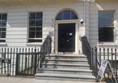 Image of a building with stairs and a black door