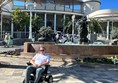 Image of a wheelchair user in front of a building in the sun