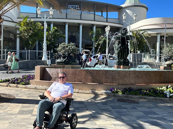 Image of a wheelchair user in front of a building in the sun