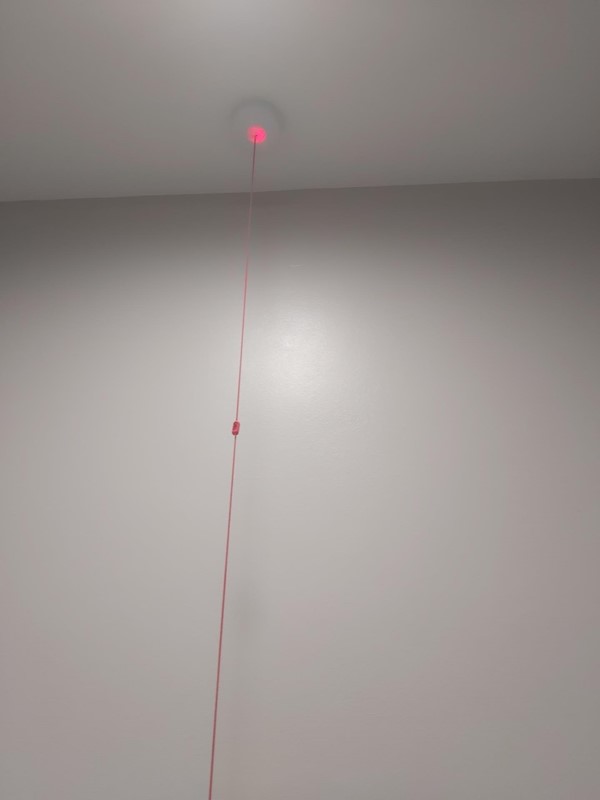 A red emergency cord against a white wall