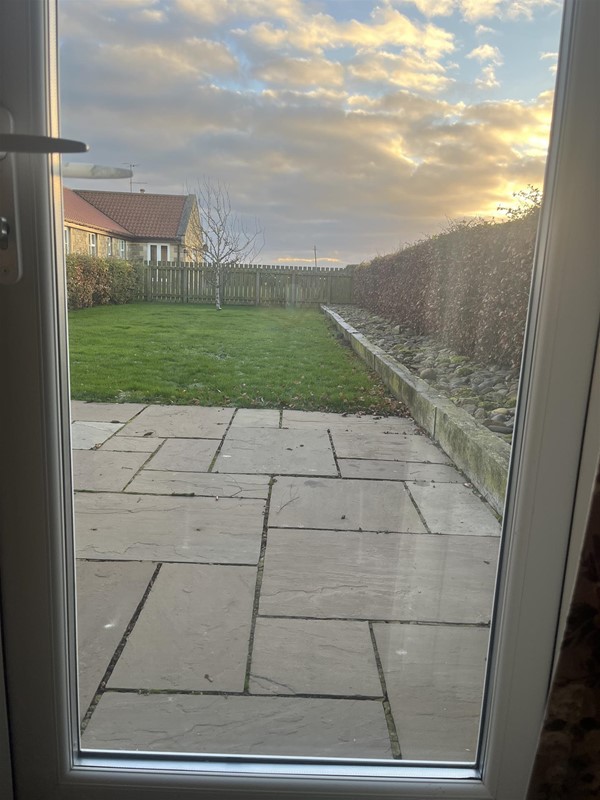 Image of a patio and lawn through a window