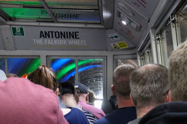 Boat entering tunnel which has blue and green light effects.