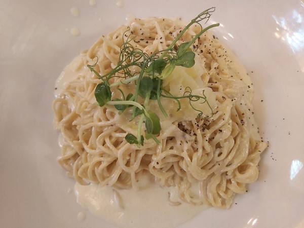 Image of a plate of noodles with a sprig of pea sprouts