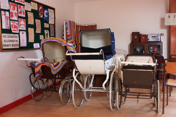 Inside the community hall. Three prams parked up.