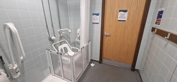 Image of accessible shower with a chair in it from within the accessible toilet.