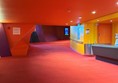 Image of a red carpeted hallway with a red wall and a blue sign