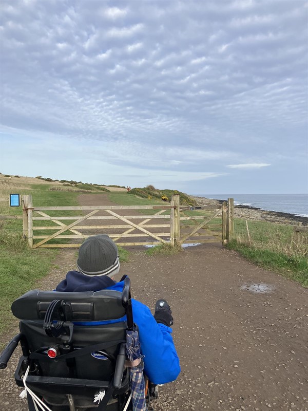 Image of a wheelchair user approaching a gate