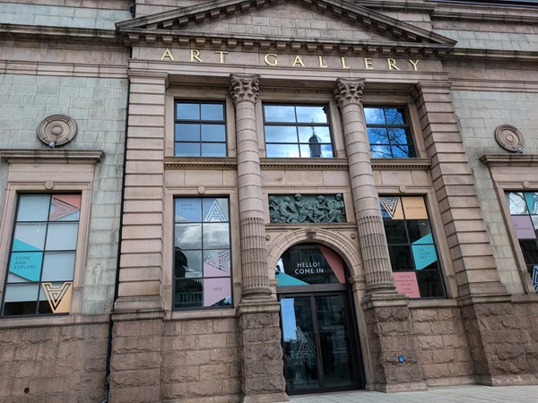 Exterior image of Aberdeen Art Gallery. an old sandstone with large windows and gold lettering that reads ART GALLERY above the door.