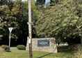 Image of a sign on a pole next to a stone wall