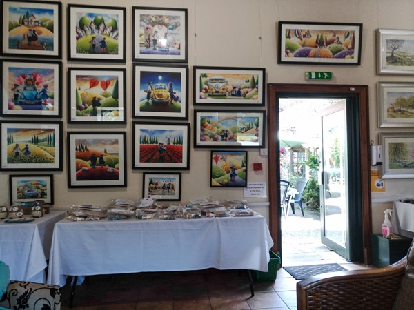 Main door is open. The walls around are covered with brightly coloured framed pictures.