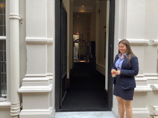 A woman in a blue skirt suit uniform in front an open door