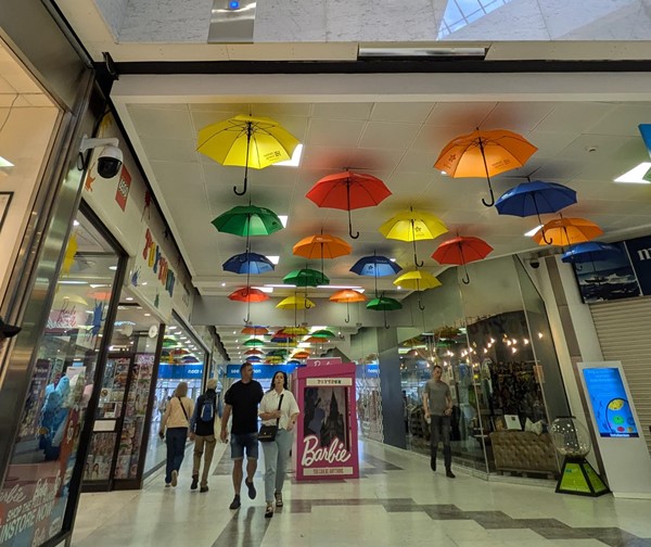 Image of the inside of the centre, tiled black and white floors, with colorful umbrellas on the white roof