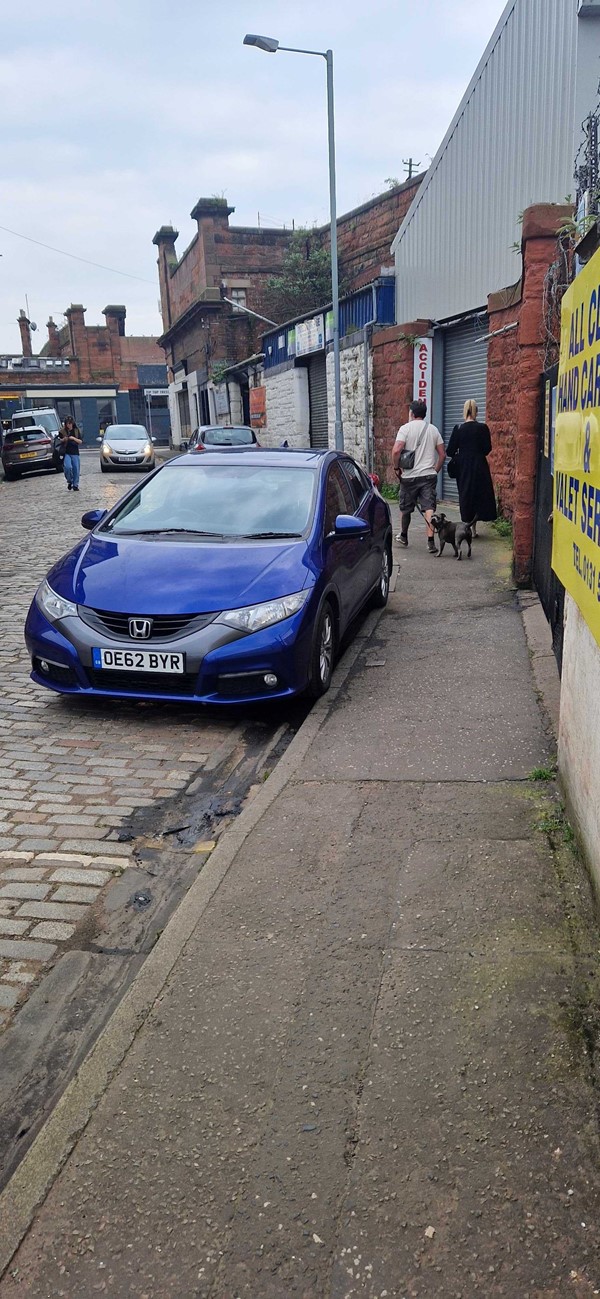 Image of pavement outside of the venue - a blue car is parked very close up to the pavement.