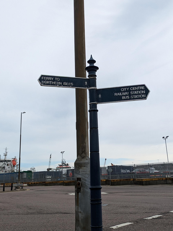 A sign pointing left to the ferry terminal and right to the city centre