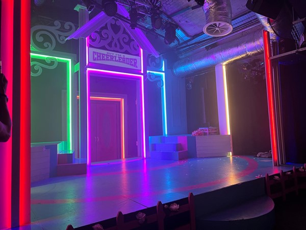 A small stage lit up in rainbow colours