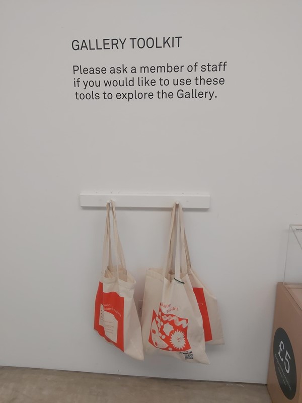 Image of a  sign on a wall and three bags on hooks