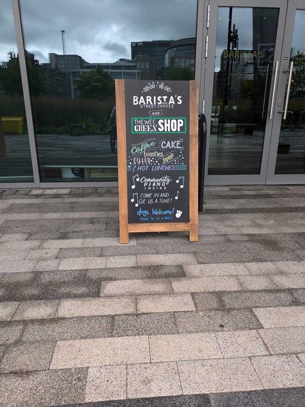 A sandwich board showing the name of the coffee show, stating they're dog friendly.