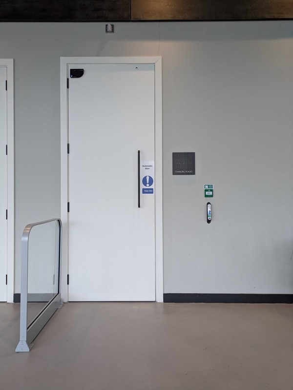 The entrance to the Changing Places Toilet. A white door with a touch pad to the right, and a small sign that reads Changing Places Toilet