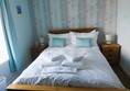 Image of a double bed in a guest room with white sheets and pillows