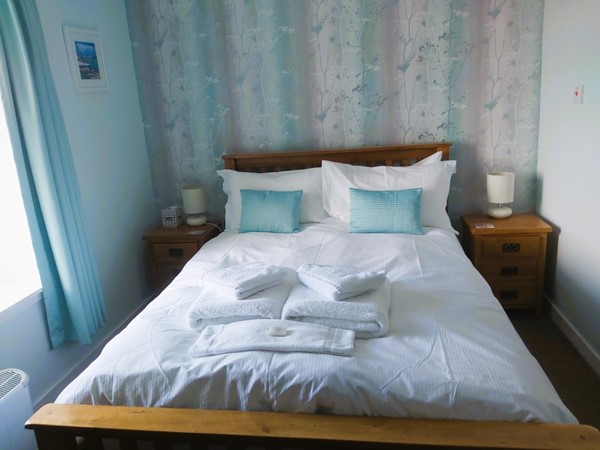 Image of a double bed in a guest room with white sheets and pillows