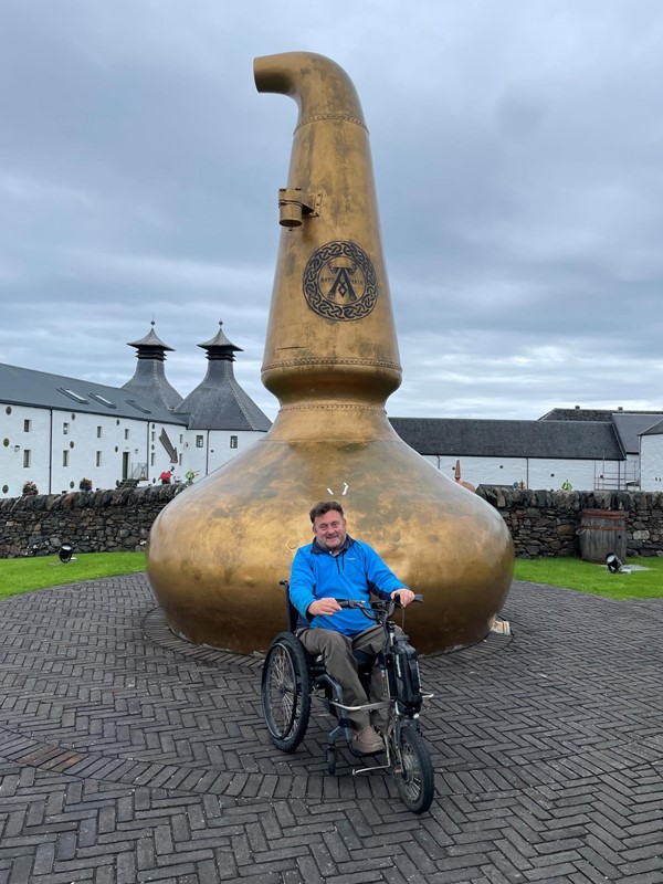 Image of a person in a wheelchair in front of a sculpture