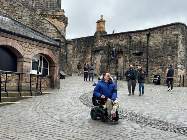 Paul wheels down the slope and across the cobbles as he descends from the upper level of the castle