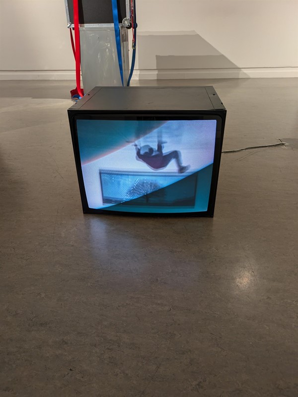 Image of an installation - a screen on the floor showcasing a person falling.