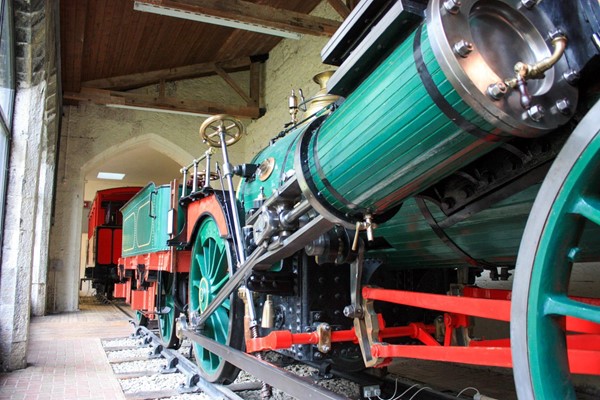 Steam train with path down side which narrows where stone columns are.