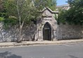 Image of a stone wall with a door and trees