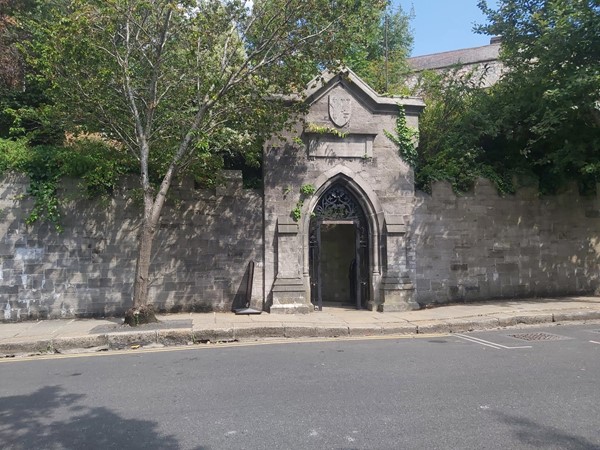 Image of a stone wall with a door and trees